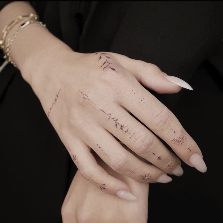 a woman's left hand with tattoos on it and her right hand in the middle