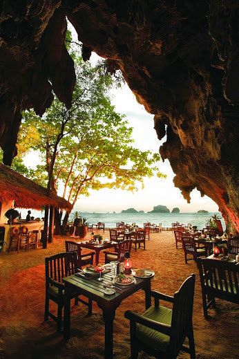 an outdoor dining area with tables and chairs on the beach