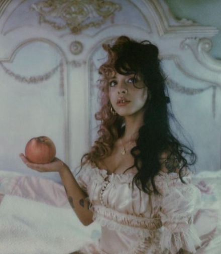 a woman sitting on a bed holding an apple