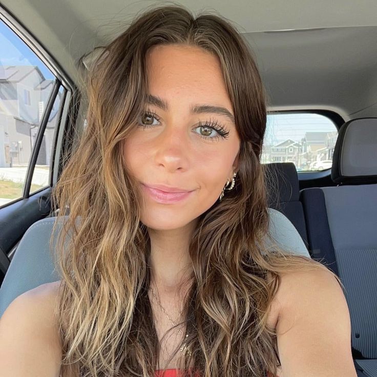 a woman sitting in the back seat of a car looking at the camera with a smile on her face