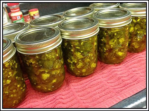 several jars filled with pickles sitting on top of a pink towel next to cans