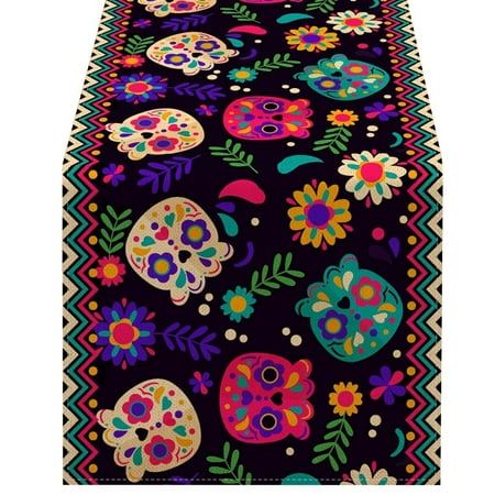 a colorful table runner with skulls and flowers on the side, along with black background