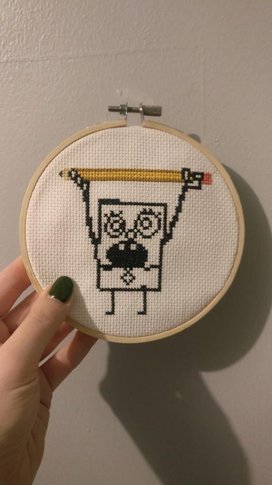 someone is holding up a cross - stitch hoop with an image of a cartoon character on it