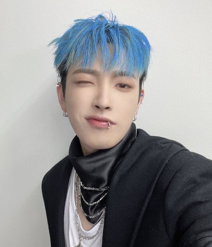 a young man with blue hair and piercings on his neck posing for the camera