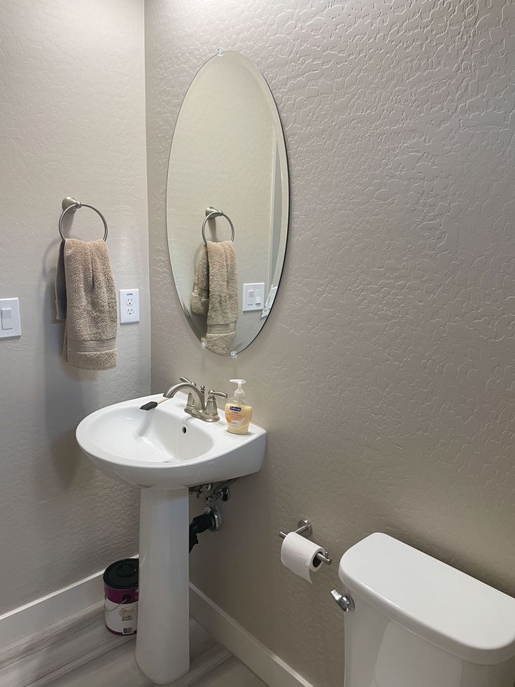 a bathroom with a toilet, sink and mirror in it's center wall area