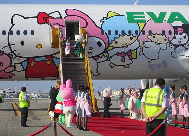 an airplane with hello kitty characters painted on it's side and people walking up the stairs