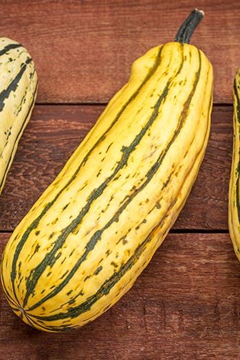 three yellow and green gourds sitting on top of a wooden table next to each other