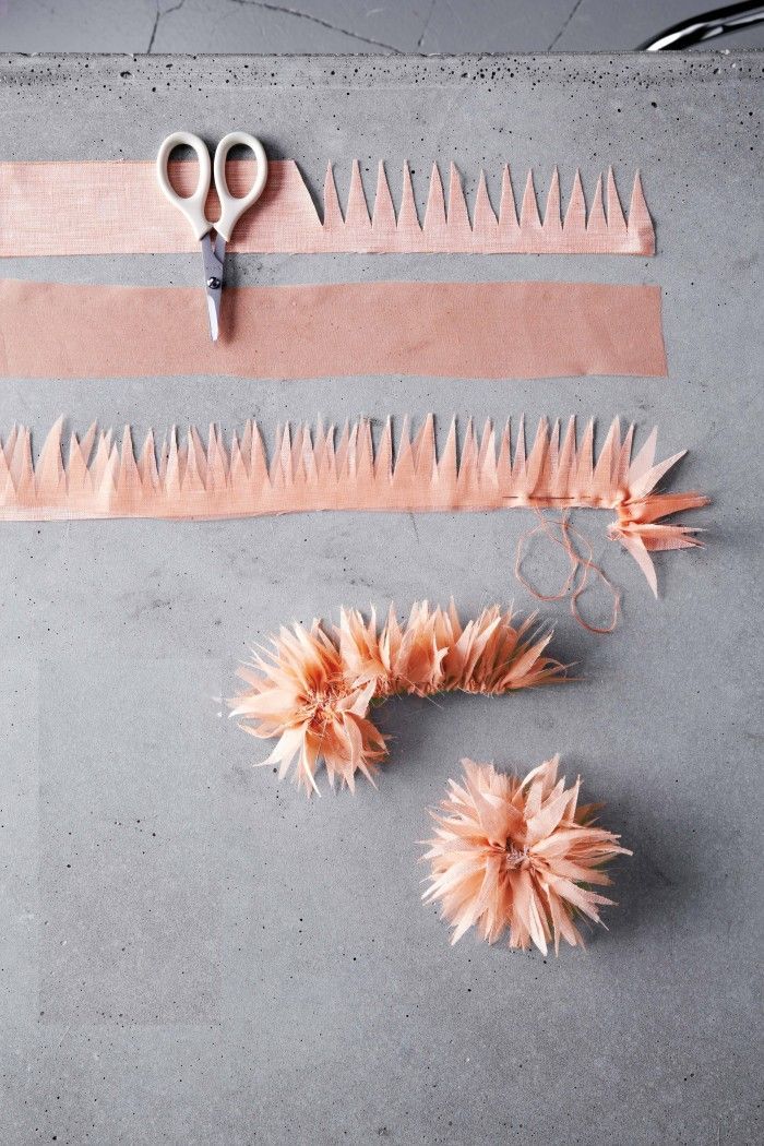 two pairs of scissors and some flowers on a gray surface with pink strips of fabric