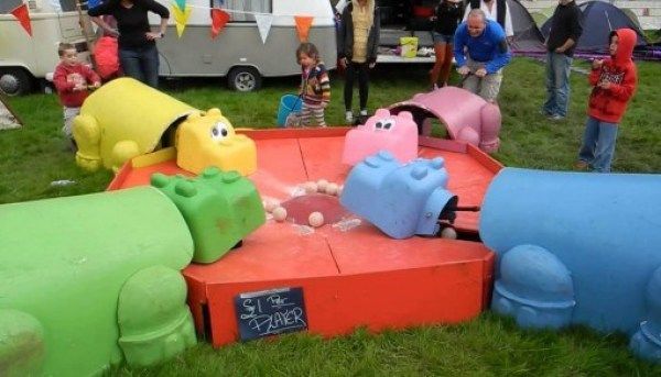 children playing in an outdoor play area with toys and people standing around the toy train