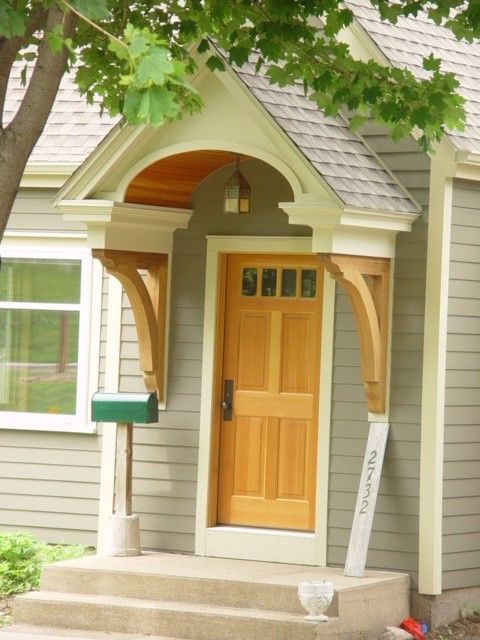 a small gray house with a yellow front door and two windows on the side of it