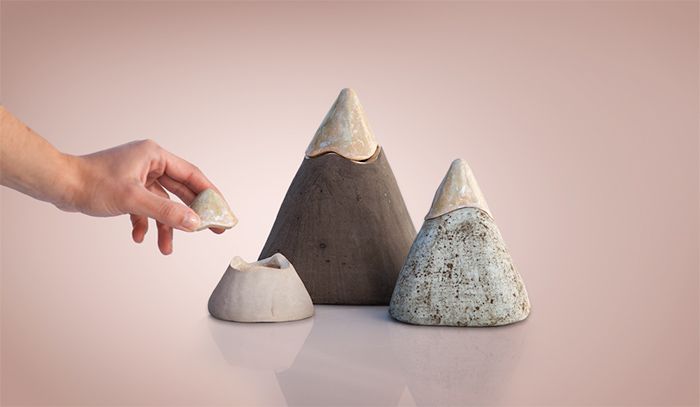 a hand is reaching for some rocks in the shape of pyramids on a white surface