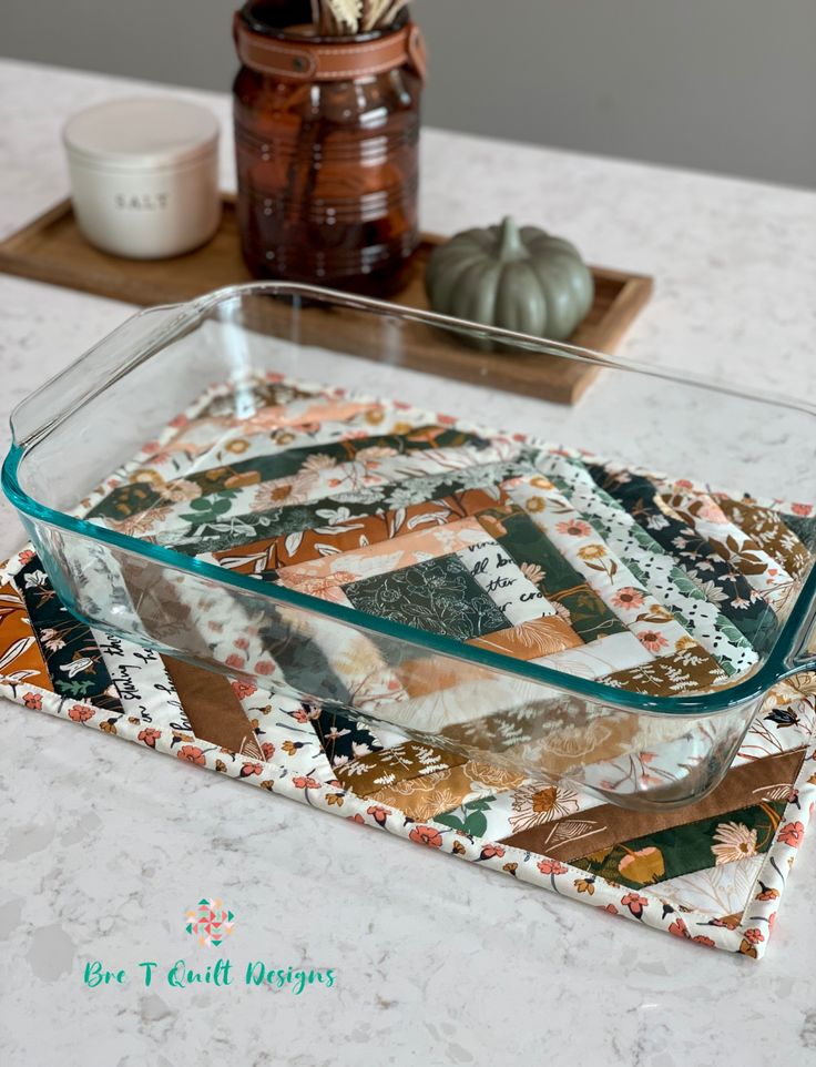 a glass dish sitting on top of a table next to a wooden tray with decorative items