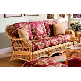 a living room with wicker furniture and pictures on the wall above it's windows