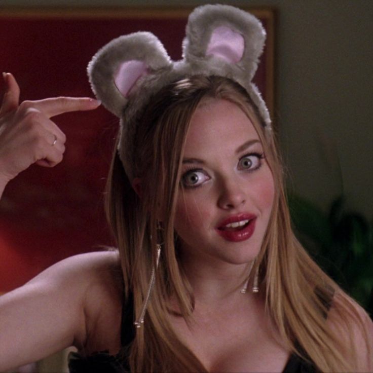 a woman with bunny ears on her head pointing to the side while wearing a black dress