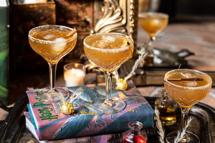 two glasses of champagne sitting on top of a tray next to books and candle holders