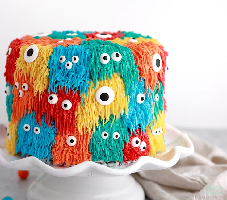 a cake decorated with colorful icing and eyeballs on top of a white plate