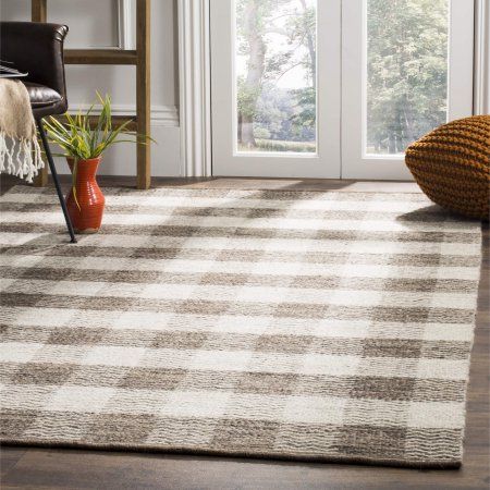 a living room area with a rug, chair and potted plant