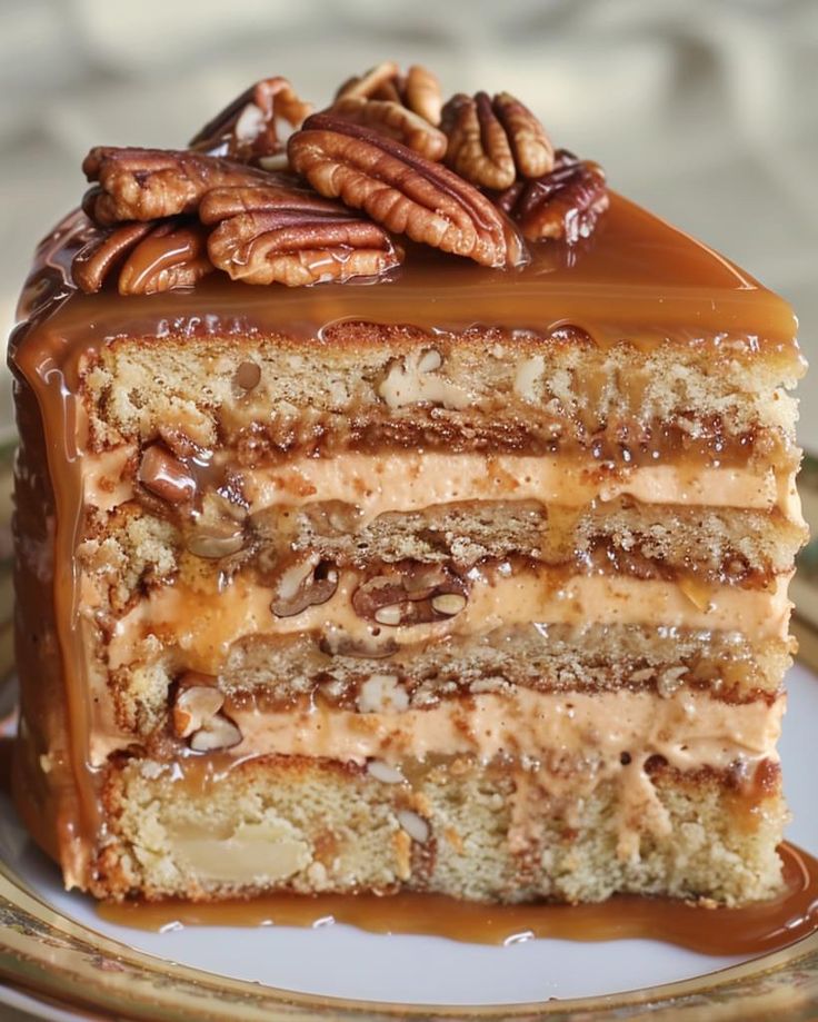 a piece of cake on a plate with pecans and caramel drizzle