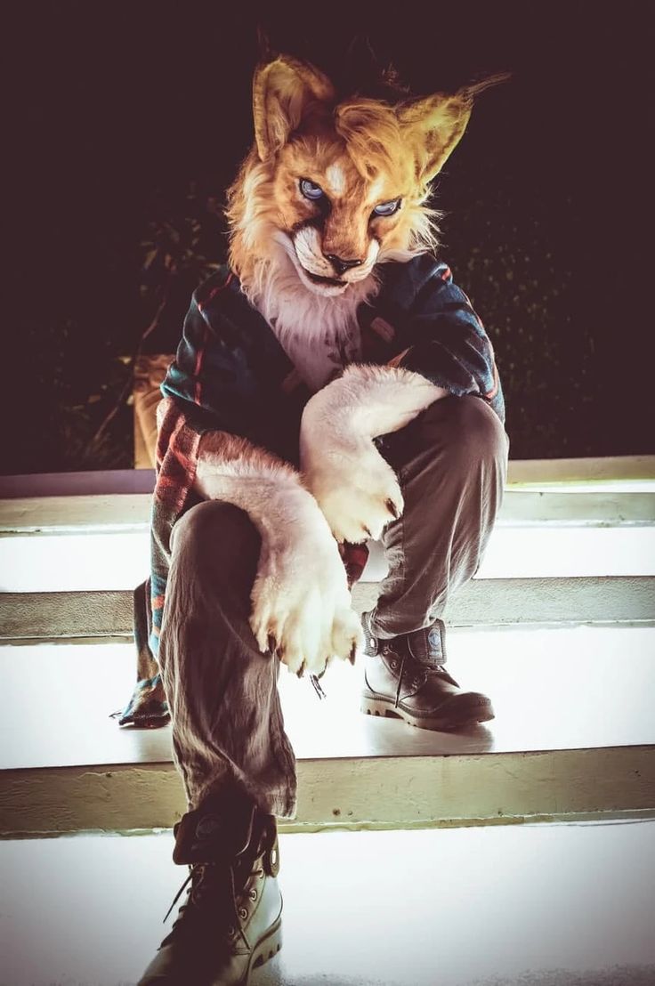 a cat sitting on top of a wooden bench next to a persons legs and shoes