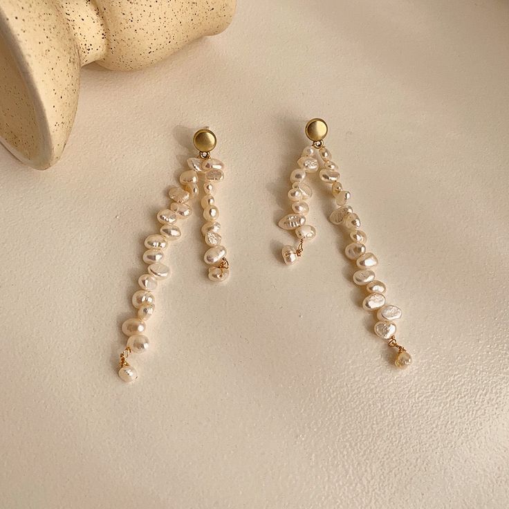 Introducing our exquisite Pearl Drop Earrings, a true masterpiece in asymmetrical elegance. These earrings are meticulously handcrafted using a combination of real freshwater pearls and 18 karat yellow gold vermeil. The unique wavy design, with its beige pearls and subtle, blurry details, evokes a sense of graceful fluidity. Embrace the artistry of asymmetry and add a touch of ethereal beauty to your style with these light white wonders. Gold Plated Dangle Earrings With Pearl Chain, Single Long Drop Pearl Earring, Single Drop Pearl Earring, Elegant Long Drop Baroque Pearl Earrings, Gold Plated Pearl Chain Dangle Earrings, Yellow Gold Long Drop Pearl Earrings, Gold Linear Earrings With Pearl Chain, Yellow Gold Pearl Dangle Earrings, Dangle Earrings With Baroque Pearl Chain