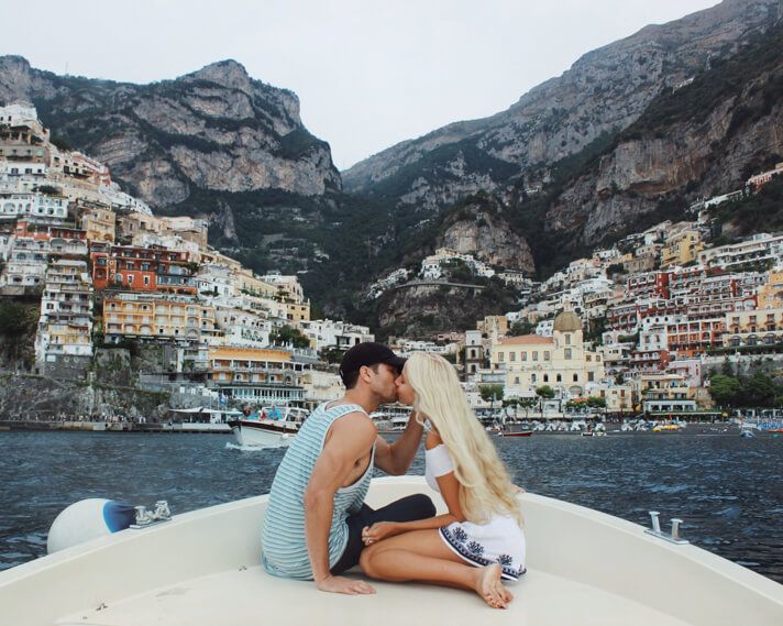 a man and woman sitting on the back of a boat in front of a city