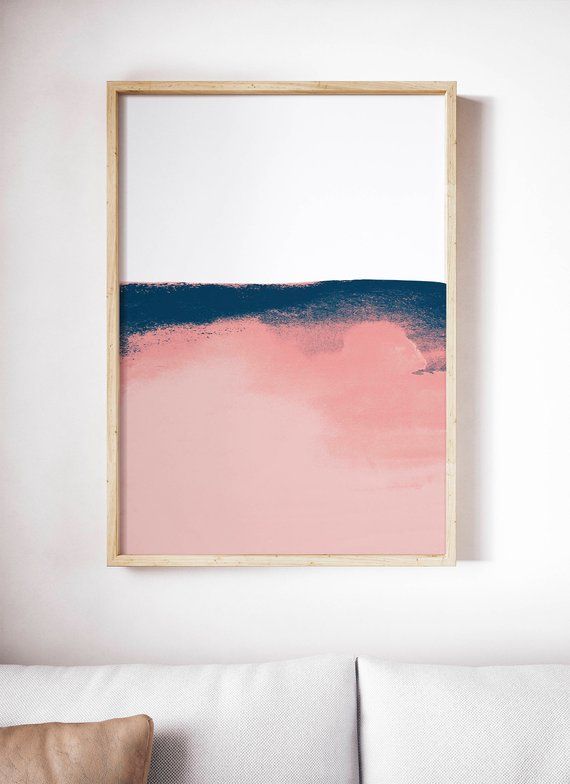 a pink and blue painting hangs on the wall above a white couch in a living room