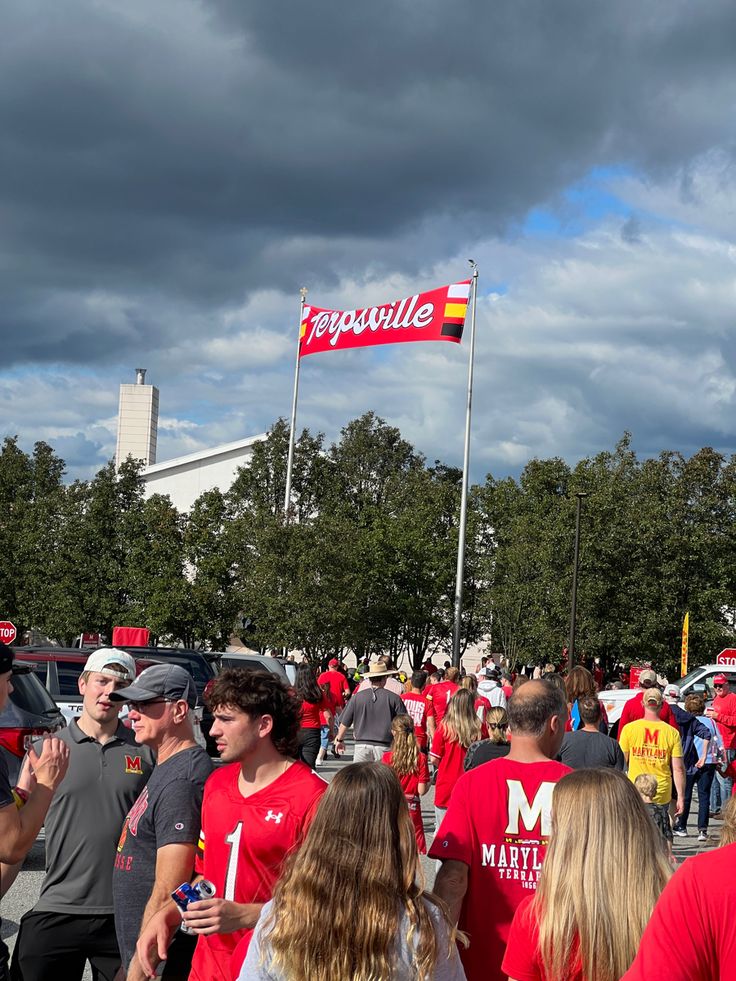 a group of people standing around each other in front of a flag on a pole