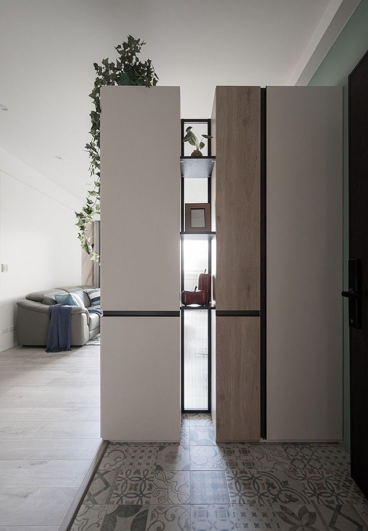 an open door leading to a living room with a plant on the wall and floor