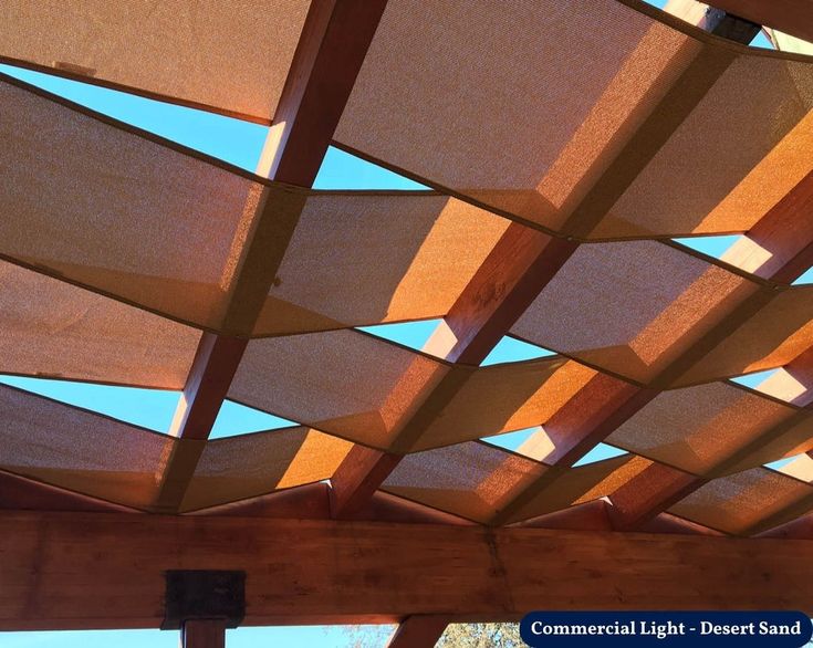 the underside of a wooden structure with sun shining through it and blue sky in the background