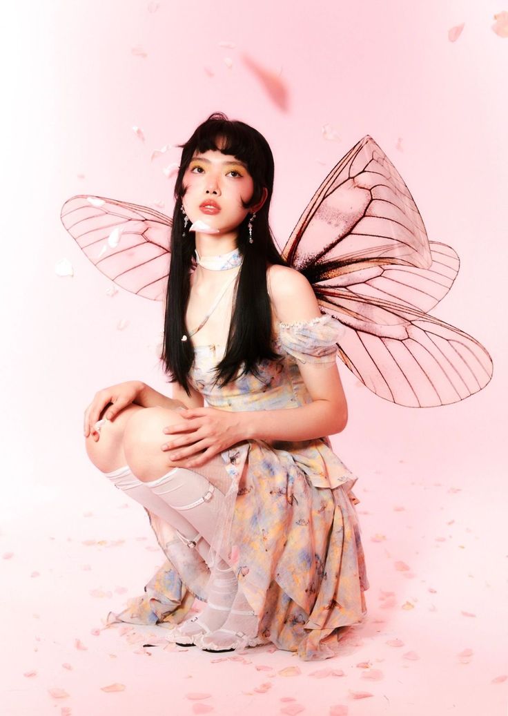 a woman dressed as a fairy sitting on the ground