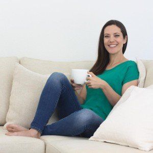 a woman sitting on a couch holding a cup