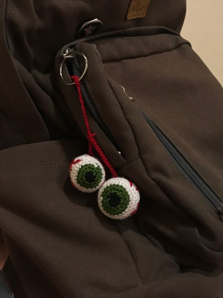 two crocheted eyeballs are attached to a backpack