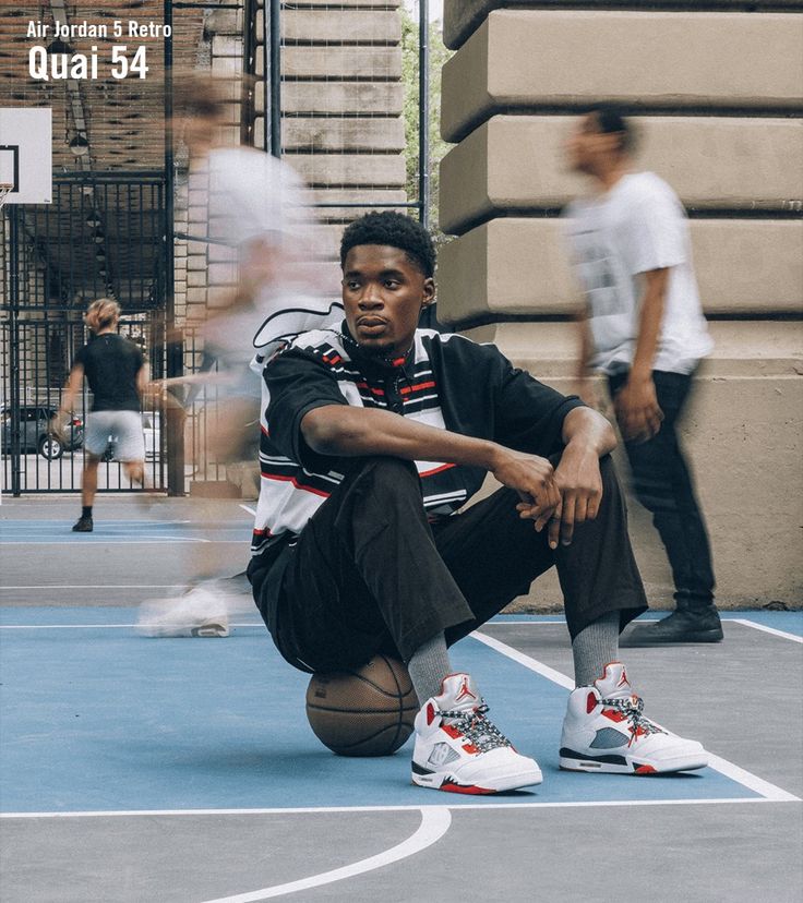 a young man sitting on top of a basketball court