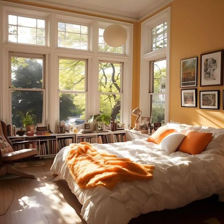 a large bed sitting in a bedroom next to two windows with pictures on the wall