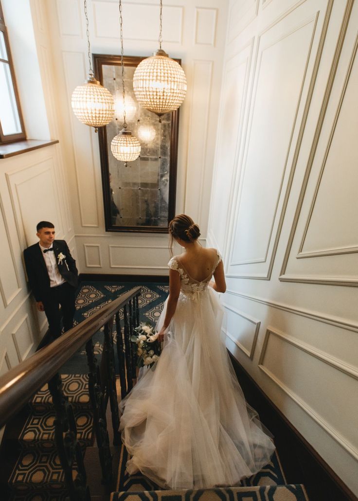 the bride and groom are walking down the stairs at their wedding ceremony in an elegant hotel