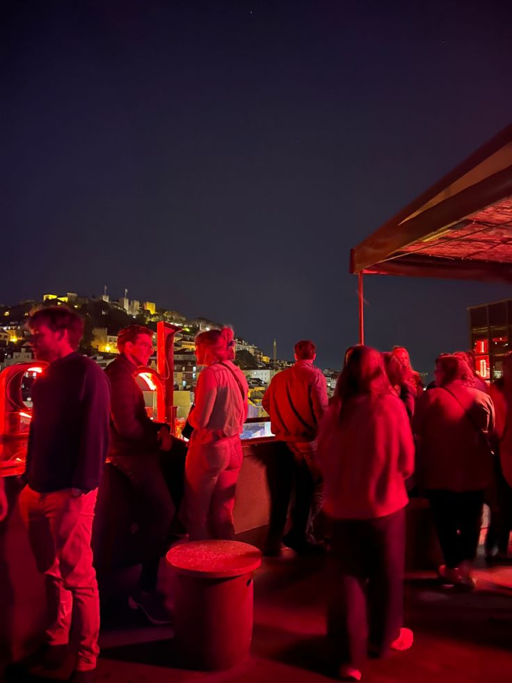 people standing on top of a roof at night with the city lights in the background