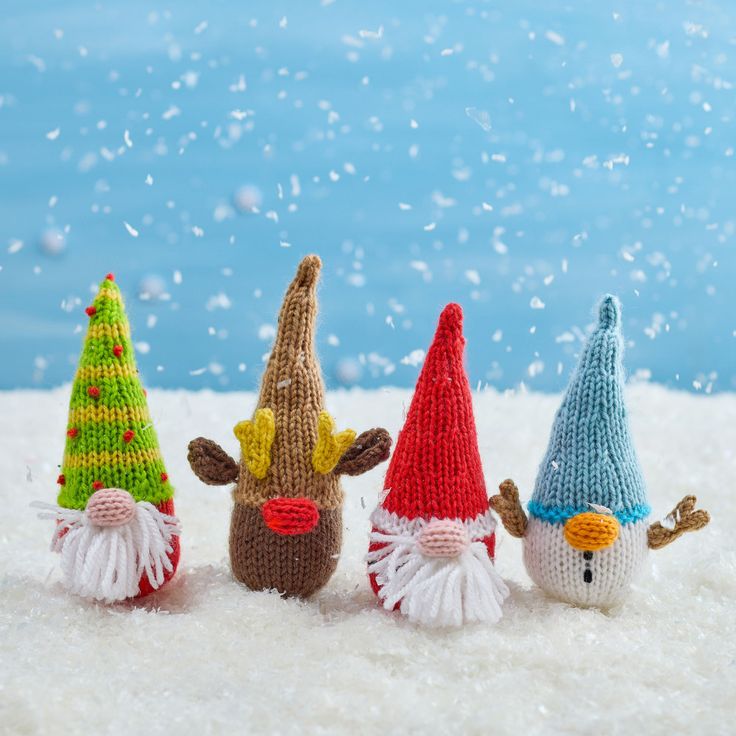 three knitted christmas gnomes standing in the snow