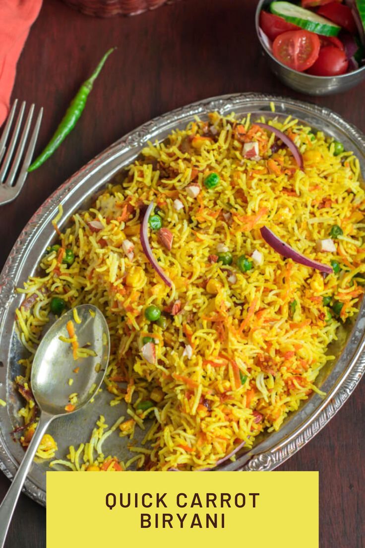 a silver plate topped with yellow rice and veggies next to a bowl of tomatoes