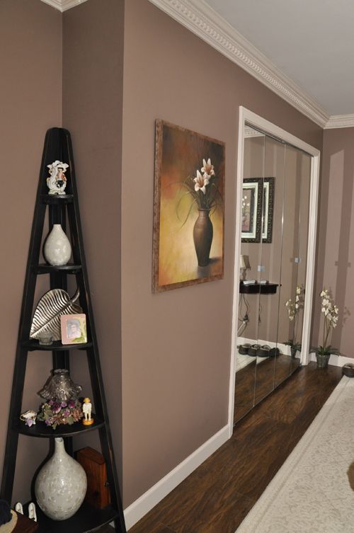 a corner of a living room with a shelf holding vases