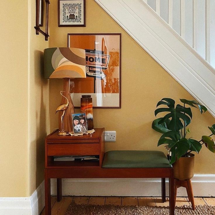 an entryway with a bench, lamp and pictures on the wall next to it