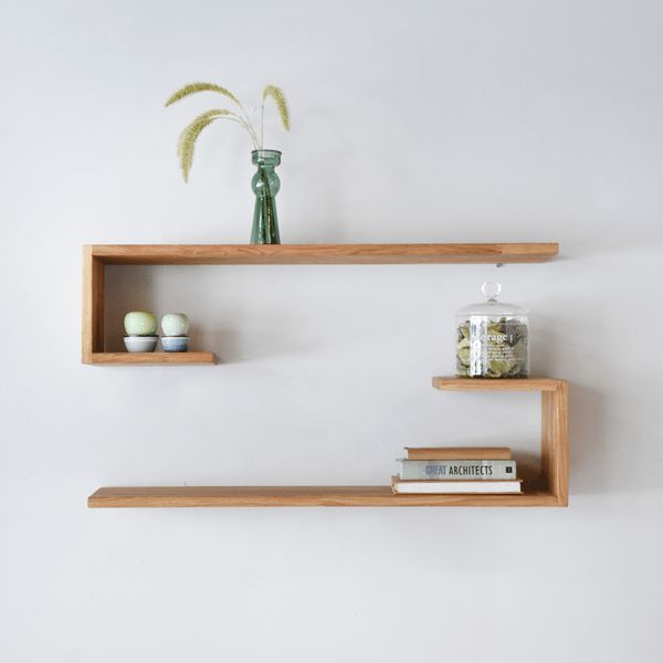 two wooden shelves with books and vases on them, one shelf has an egg in it