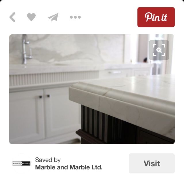 a marble counter top in a kitchen with white cabinetry and cabinets on either side