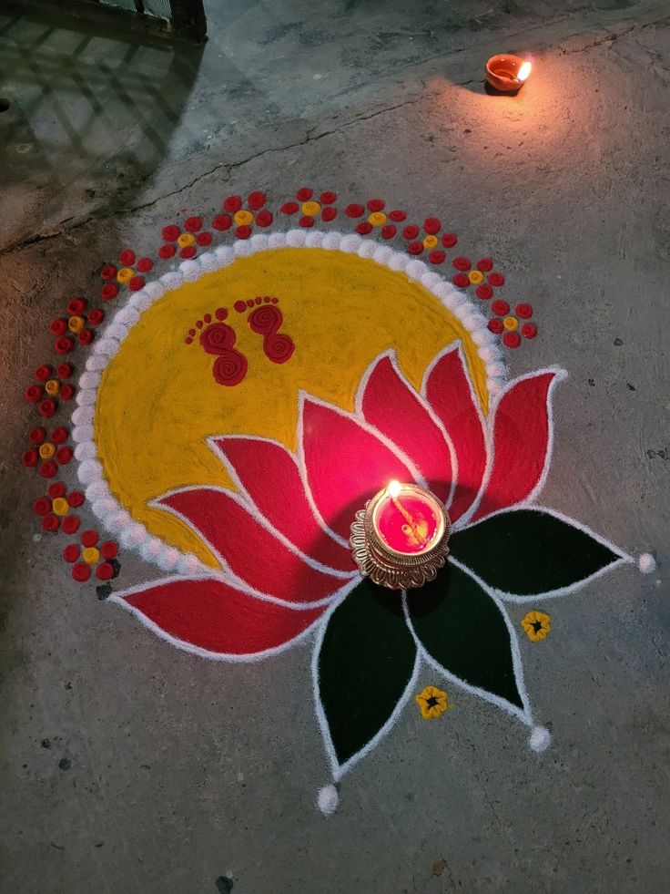 a lit candle is placed on the ground in front of a decorated rangolite