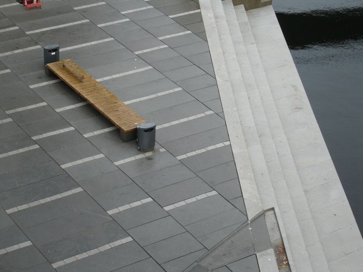 a wooden bench sitting on top of a cement walkway next to a body of water