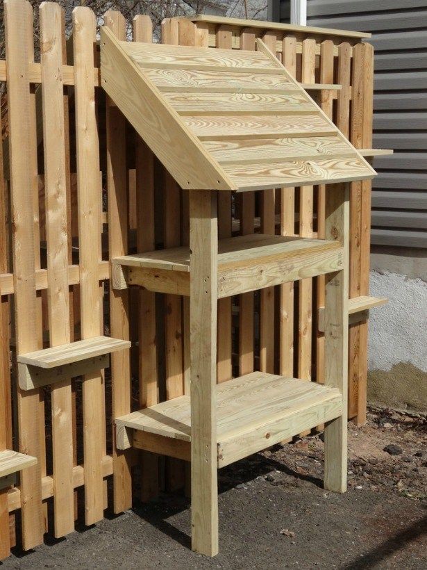 a wooden bench and shelf in front of a fenced off area with wood slats