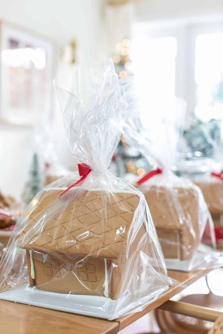 two gingerbread houses are wrapped in plastic and sitting on the dining room table for christmas