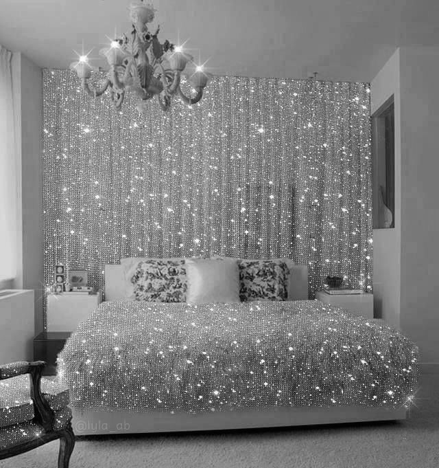 black and white photograph of a bedroom with lights on the wall, chandelier and bed