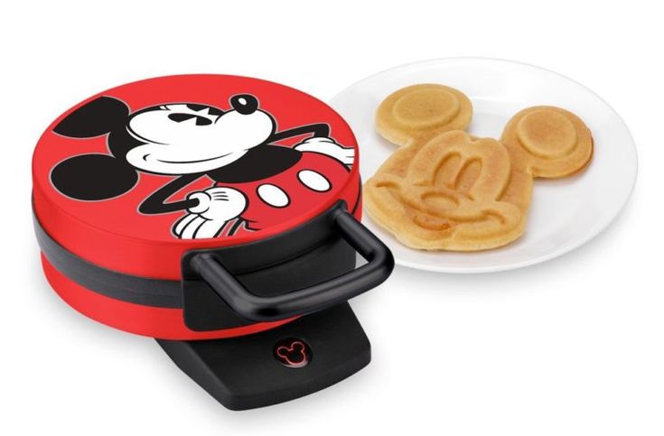 the mickey mouse waffle maker is next to a plate with some pancakes on it