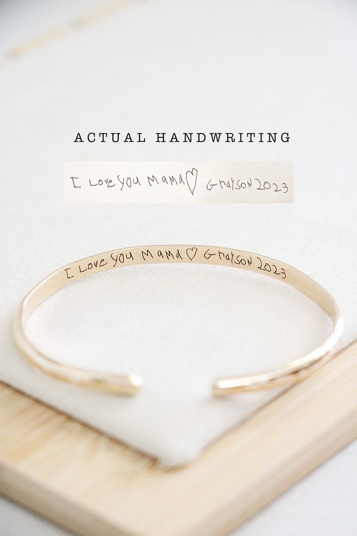 a close up of a bracelet with writing on it and a wooden board in the background