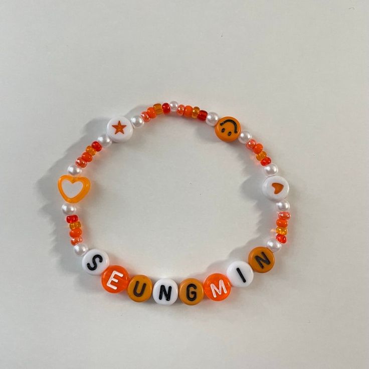 an orange and white beaded bracelet that says seunggumi with smiley faces